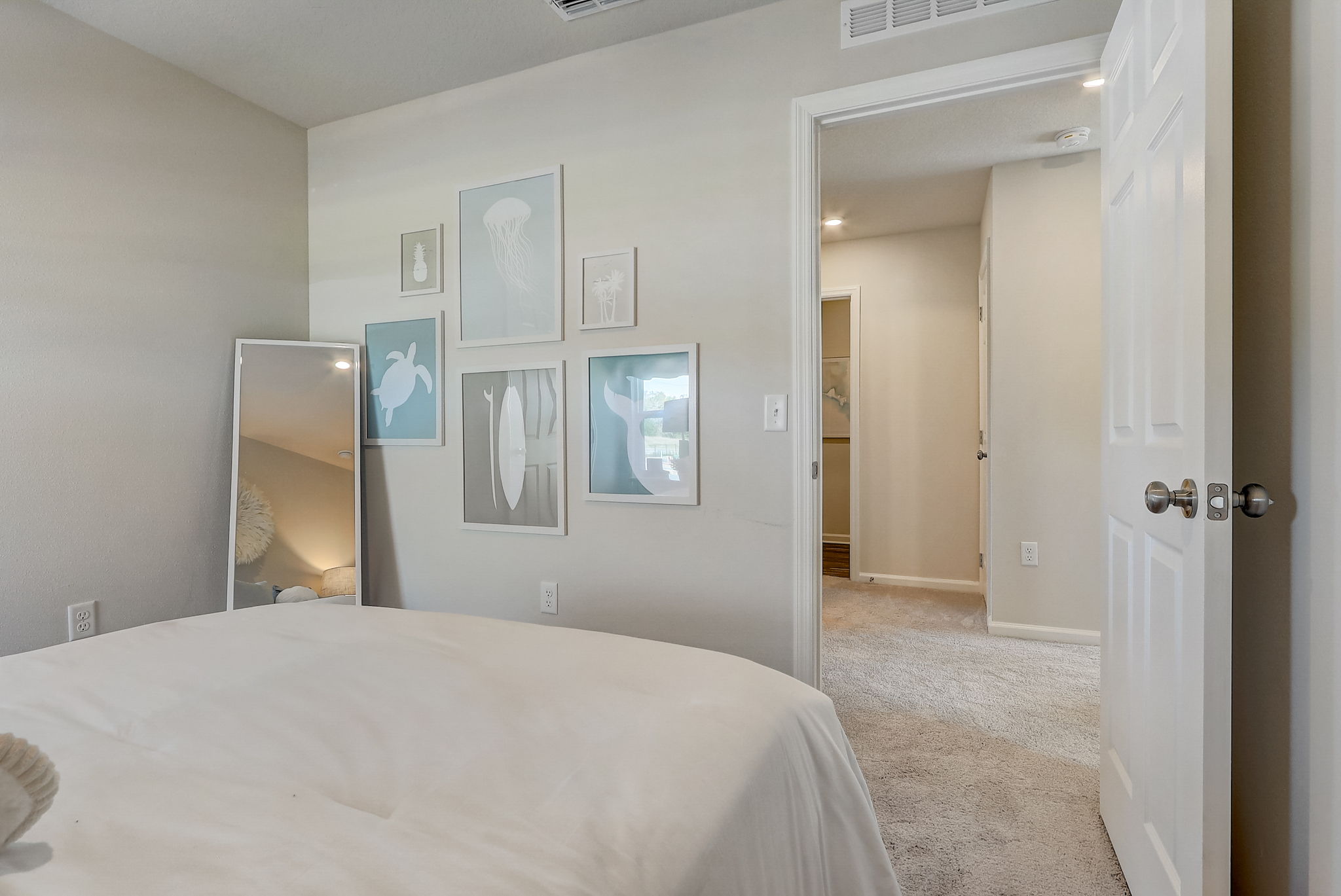 A bedroom with a mirror and a bed.