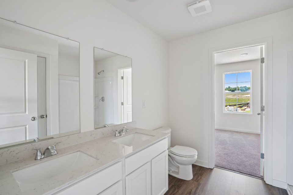 A bathroom with a sink toilet and mirror.