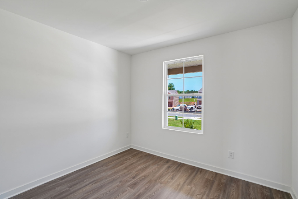 A room with a window and a wood floor.