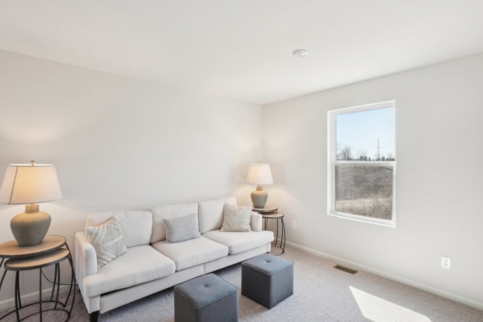 A living room with a white couch and a window.