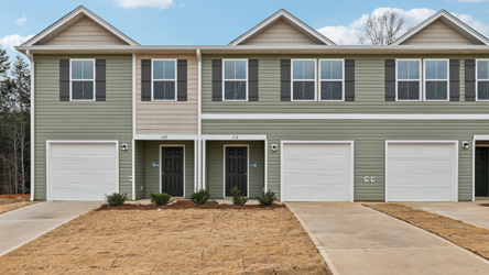 A building with garages and a dirt lot.