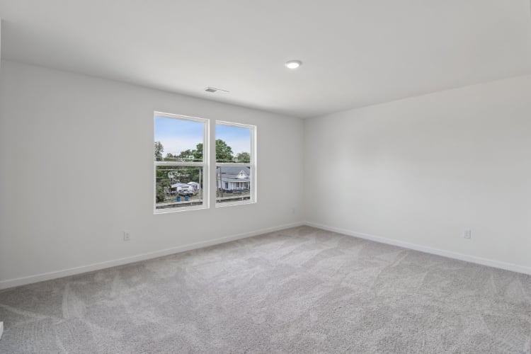A room with a window and a white wall with a picture on it.
