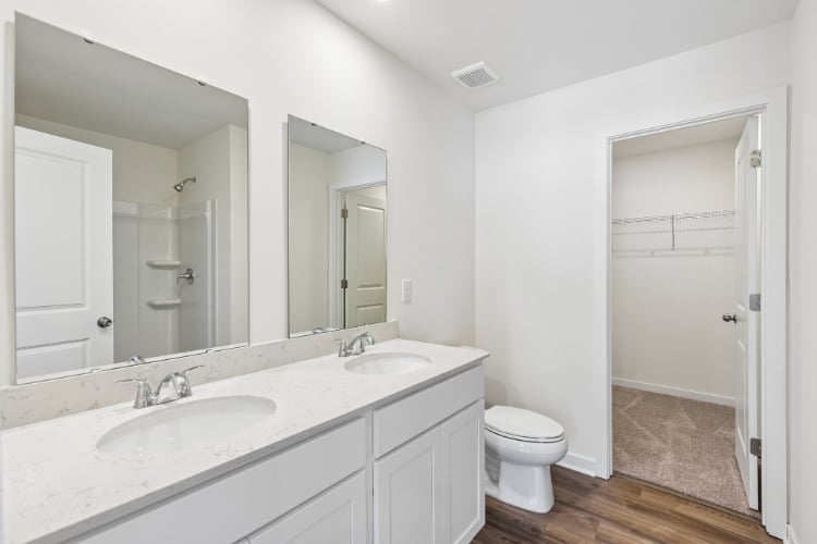 A bathroom with a sink toilet and mirror.