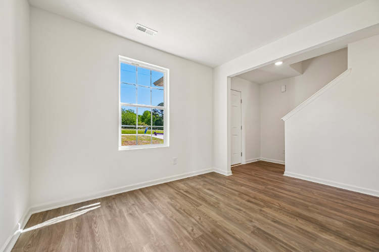 A room with a window and a wood floor.
