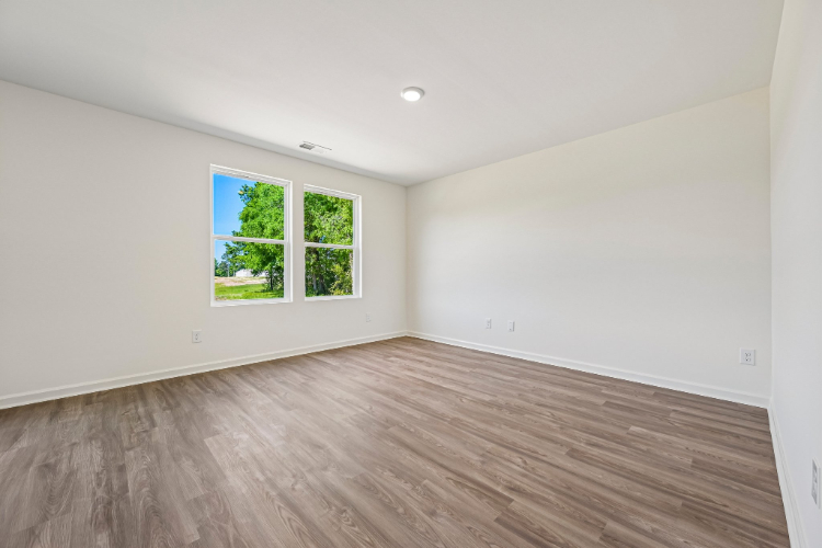 A room with a wood floor and a window with a tree outside.