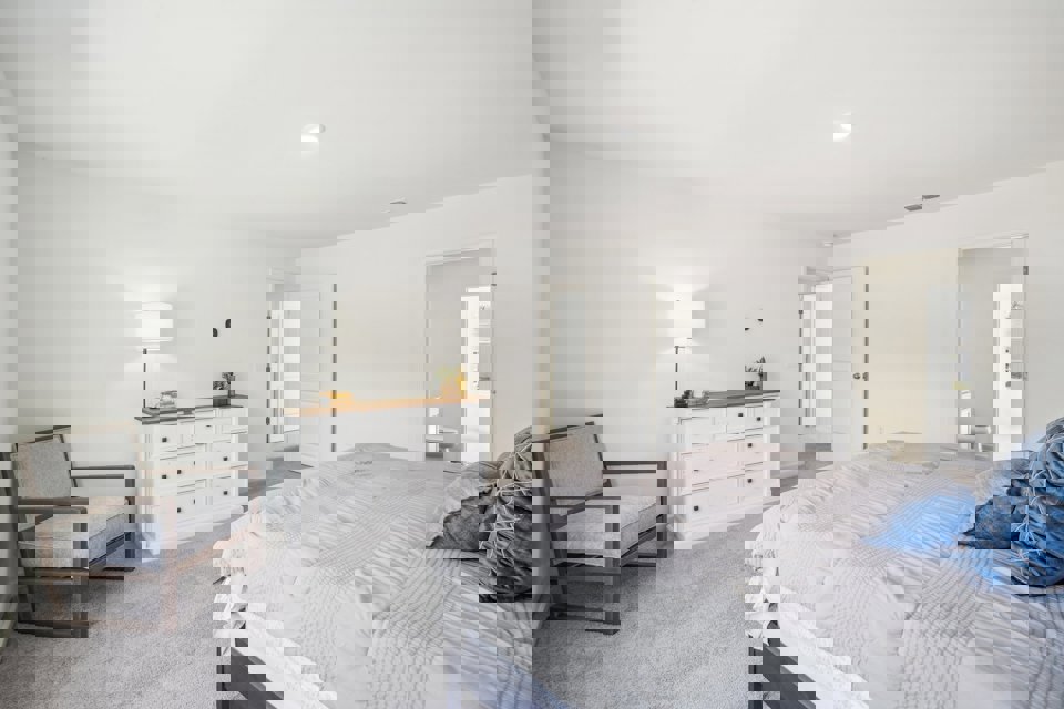 A bedroom with a bed and a chair.