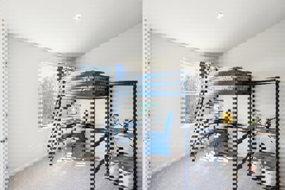 A room with a bunk bed and a chair.