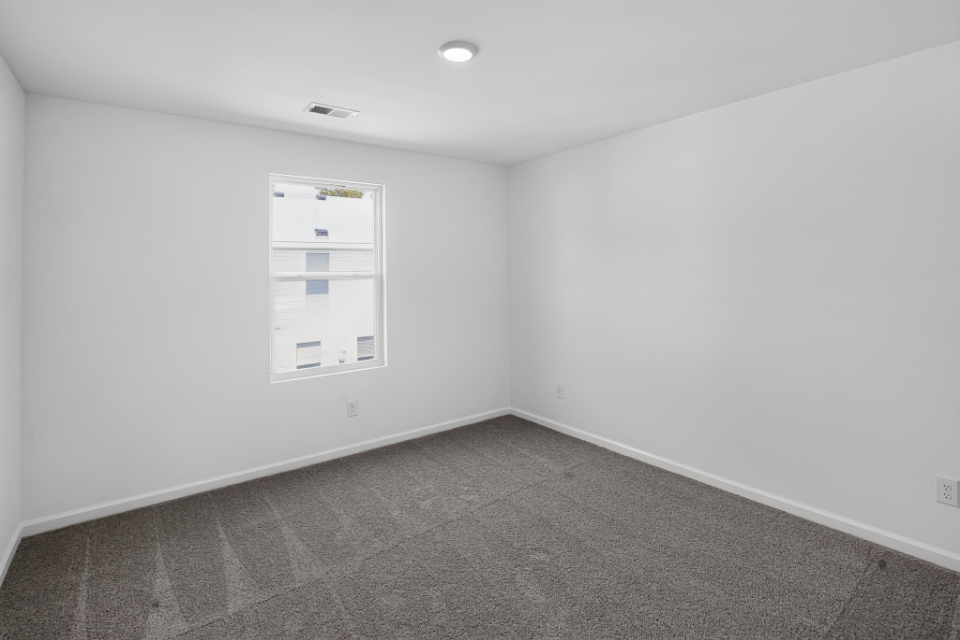 A room with a white wall and a carpet.