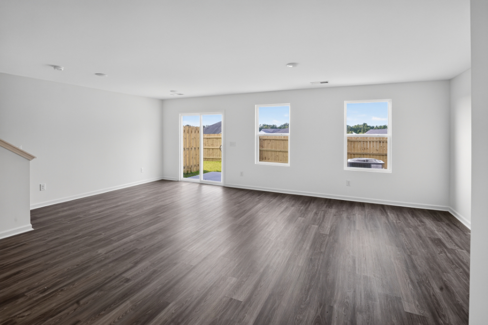 A room with a wood floor and a wood floor with a few paintings on the wall.