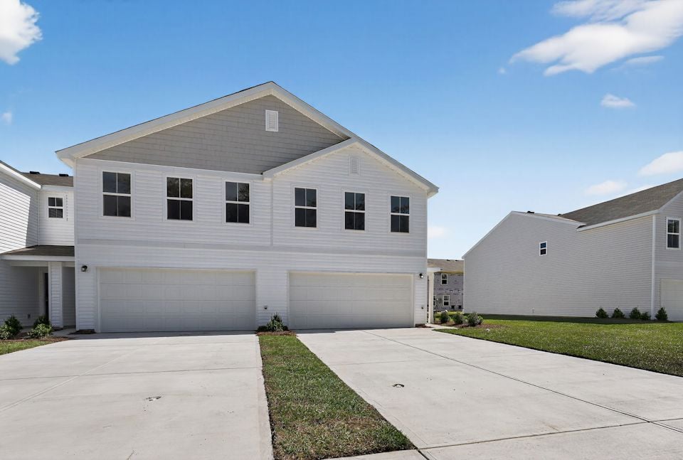 A white house with a driveway with Rockingham Meeting House in the background.