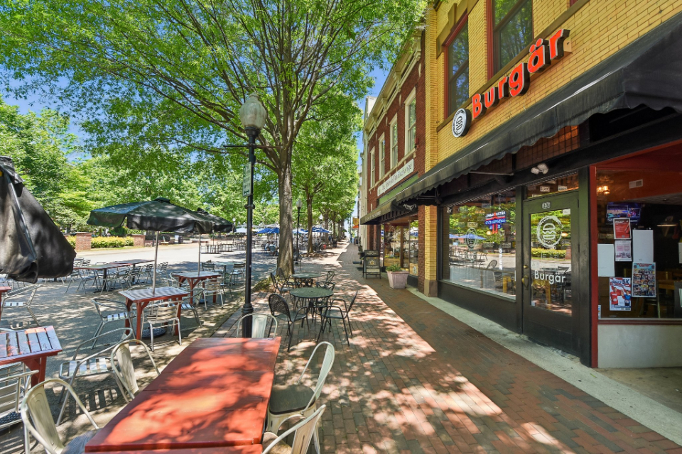 A sidewalk with tables and chairs.