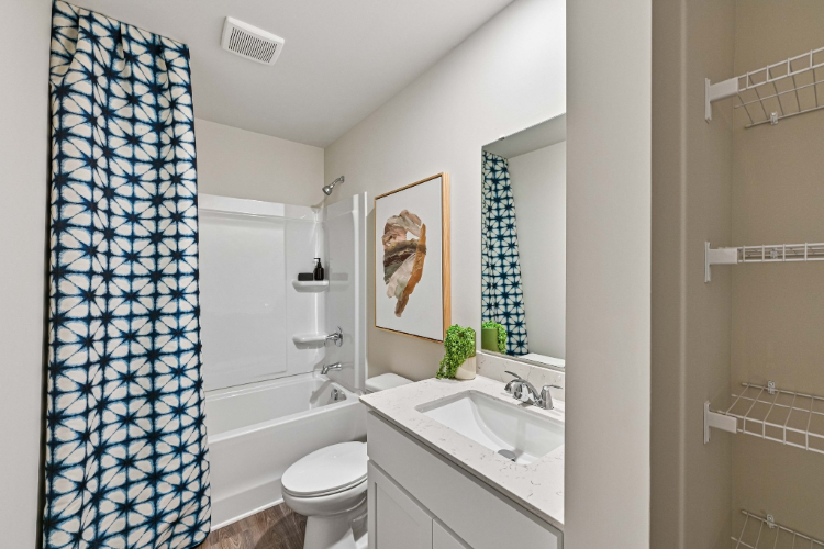 A bathroom with a sink toilet and a shower curtain.