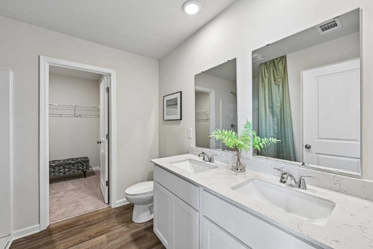 A bathroom with a sink toilet and mirror.