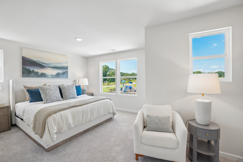 A bedroom with a bed and chairs.