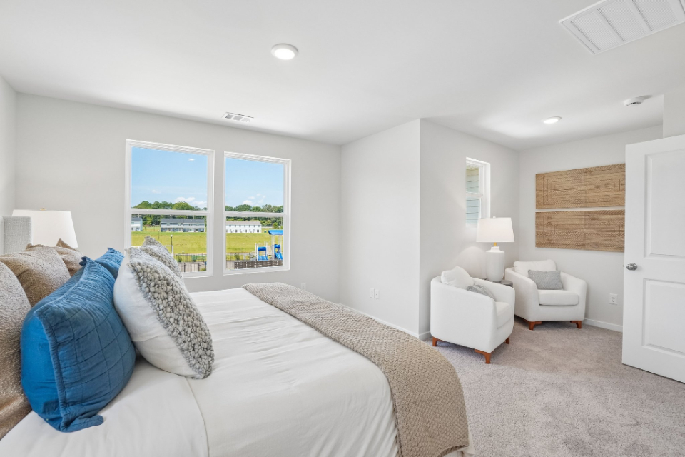 A bedroom with a bed and a chair.