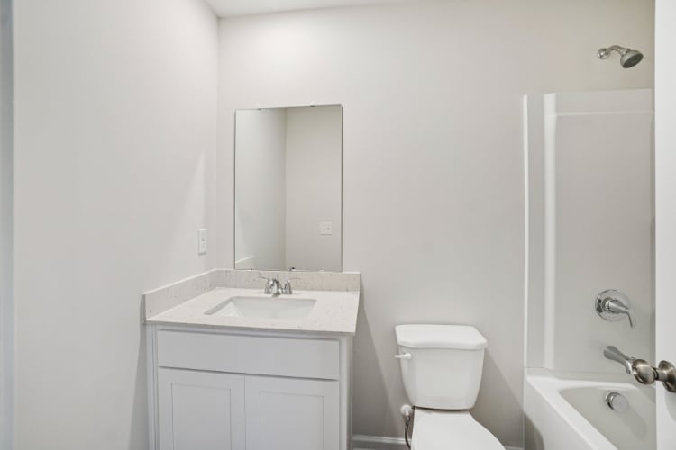 A bathroom with a toilet sink and mirror.