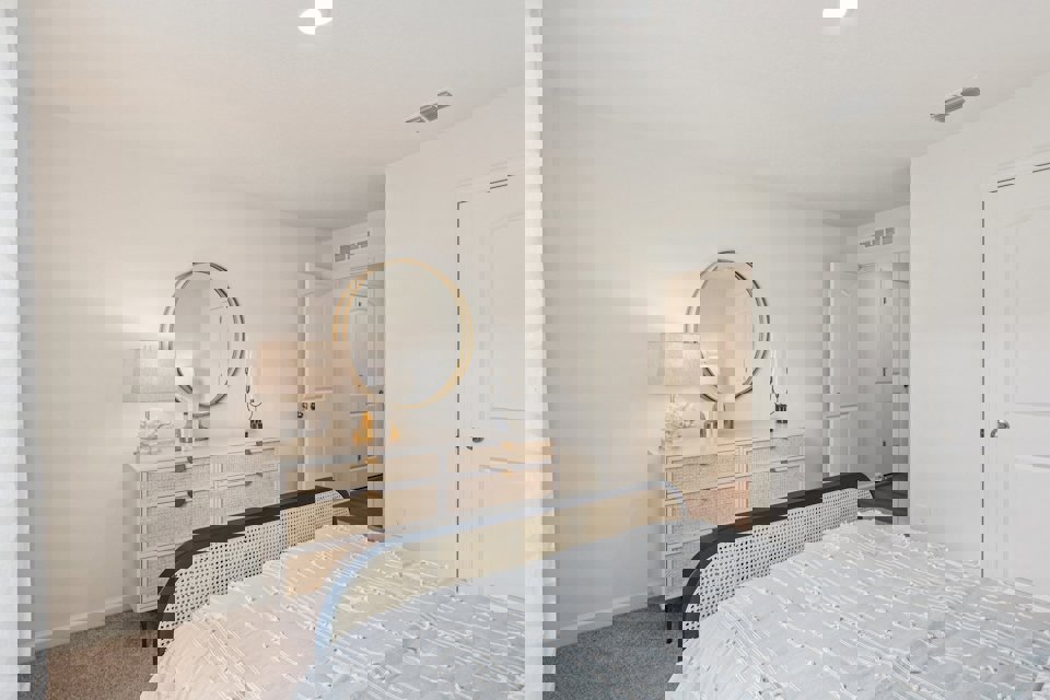 A bedroom with a mirror and a bed.