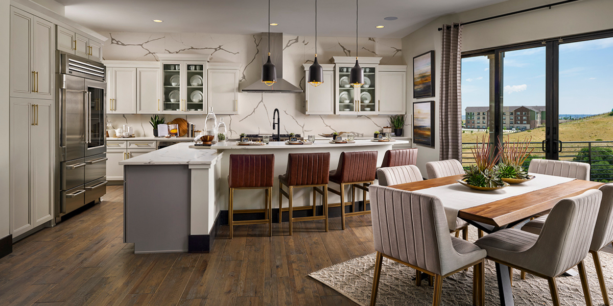 Casual dining area that flows into a stunning kitchen with center island and white accent wall. 