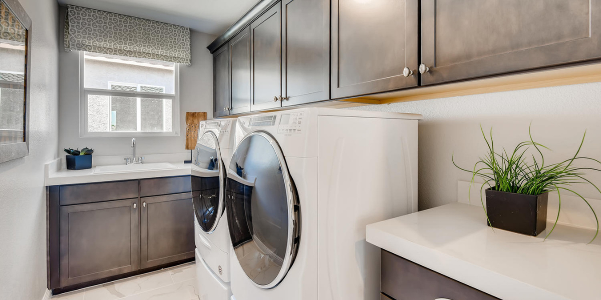 Large laundry room with matching white washer and dryer, brown cabinets and sink.  