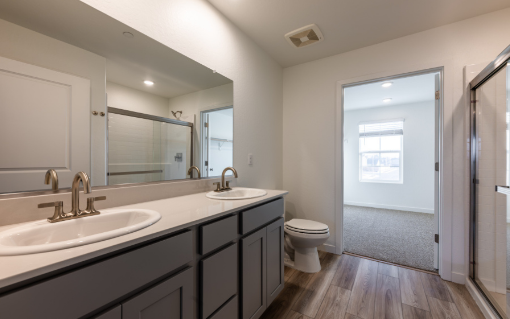 A bathroom with a sink toilet and mirror.