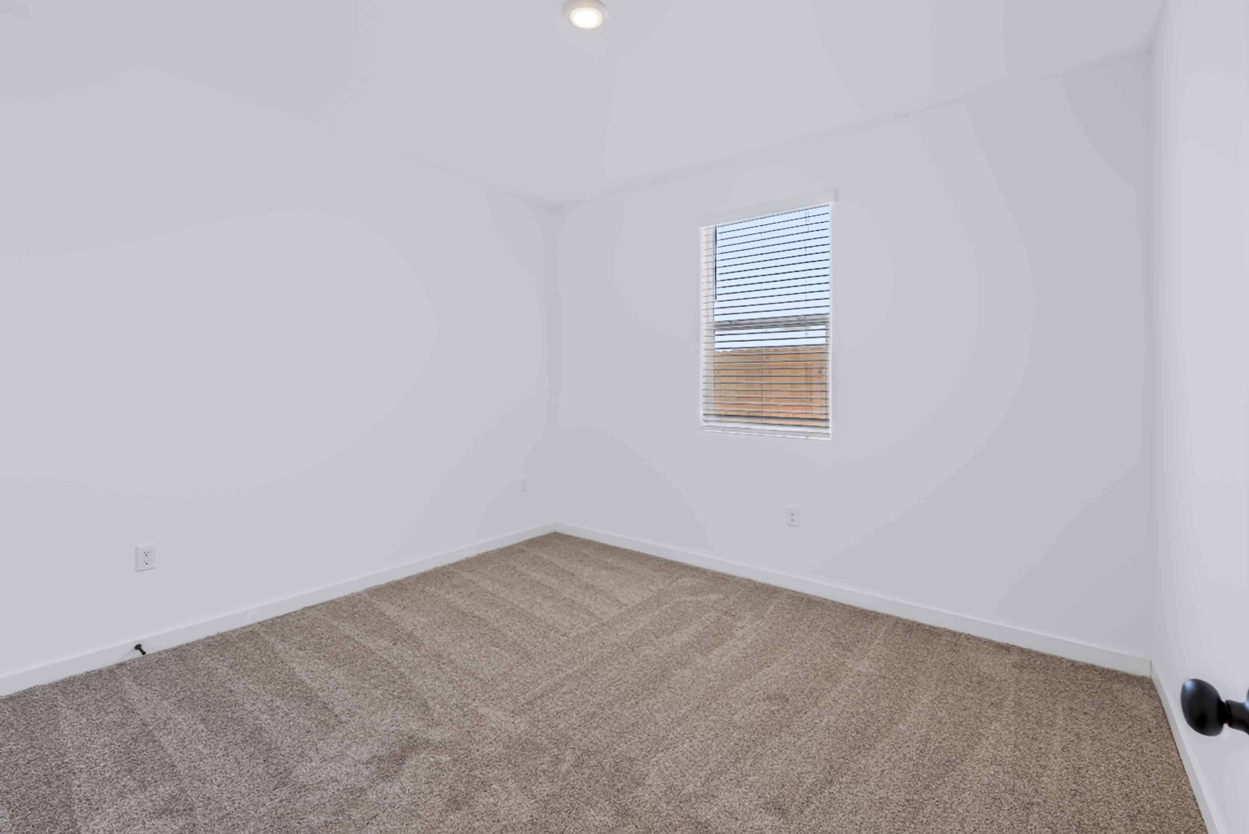 A room with a carpet and a window.