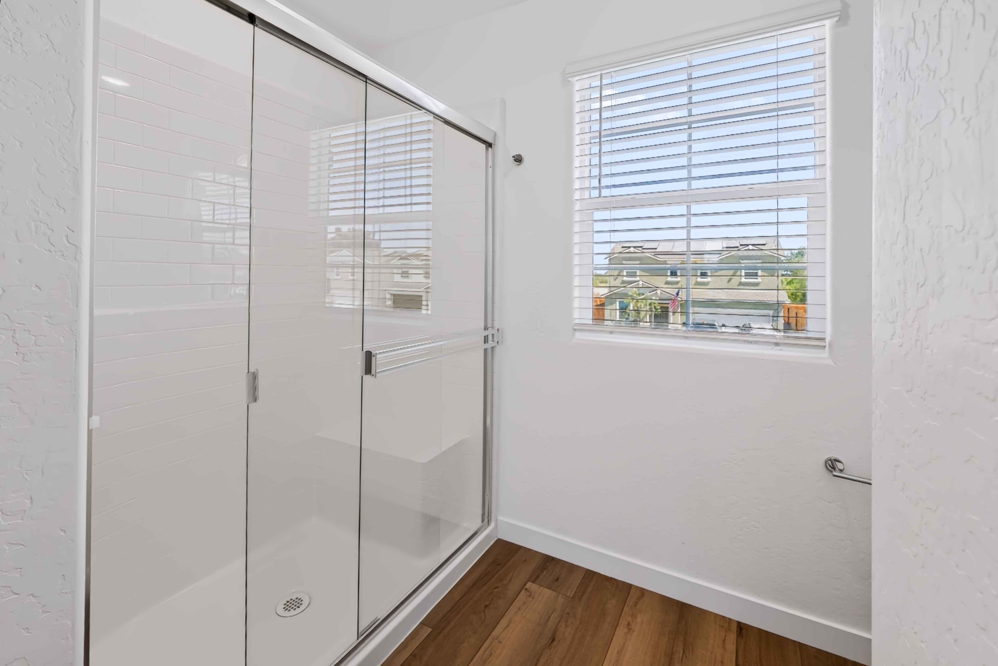 A room with a glass door and a window with a view of a city.