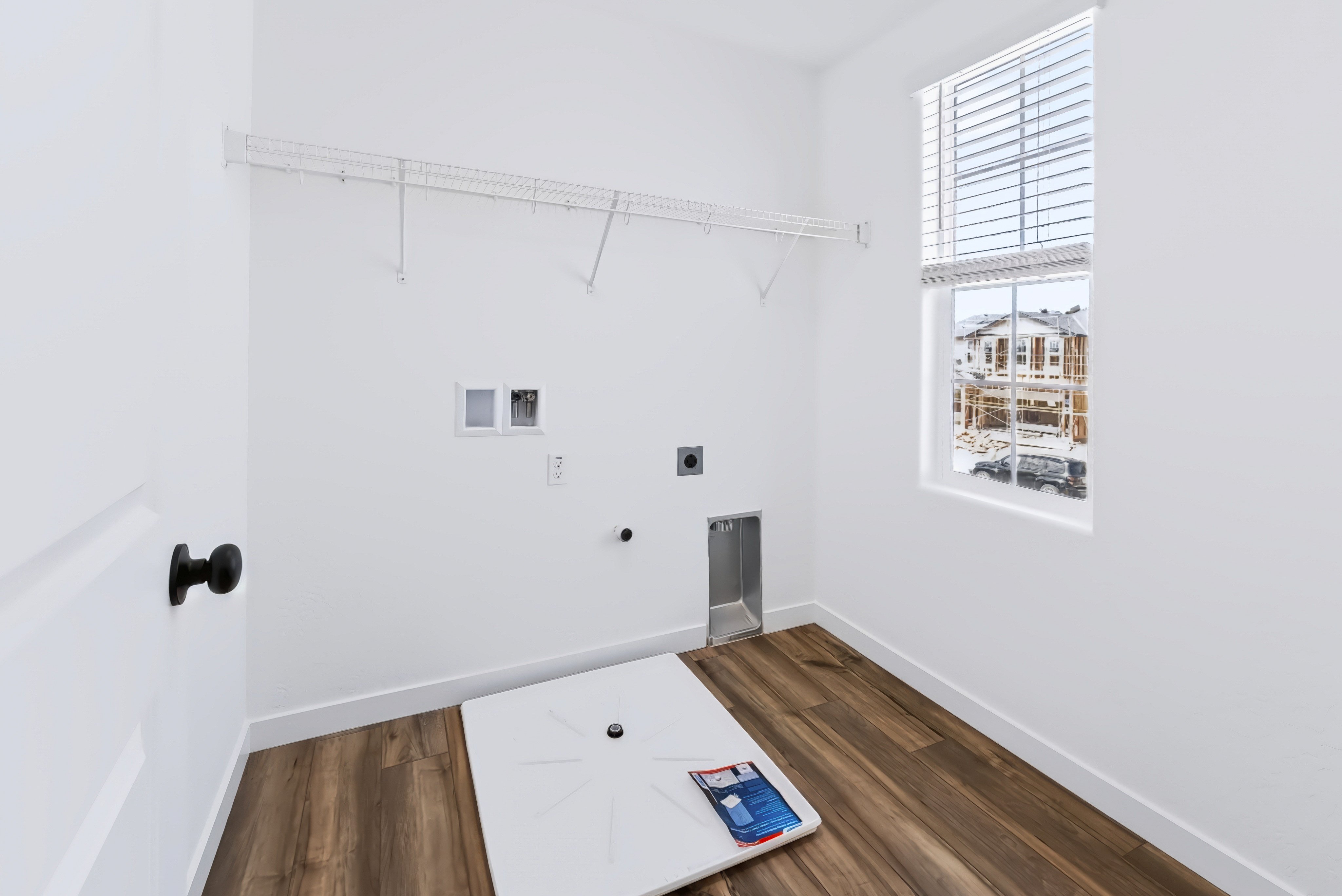 A room with a wood floor and a window with a book on it.