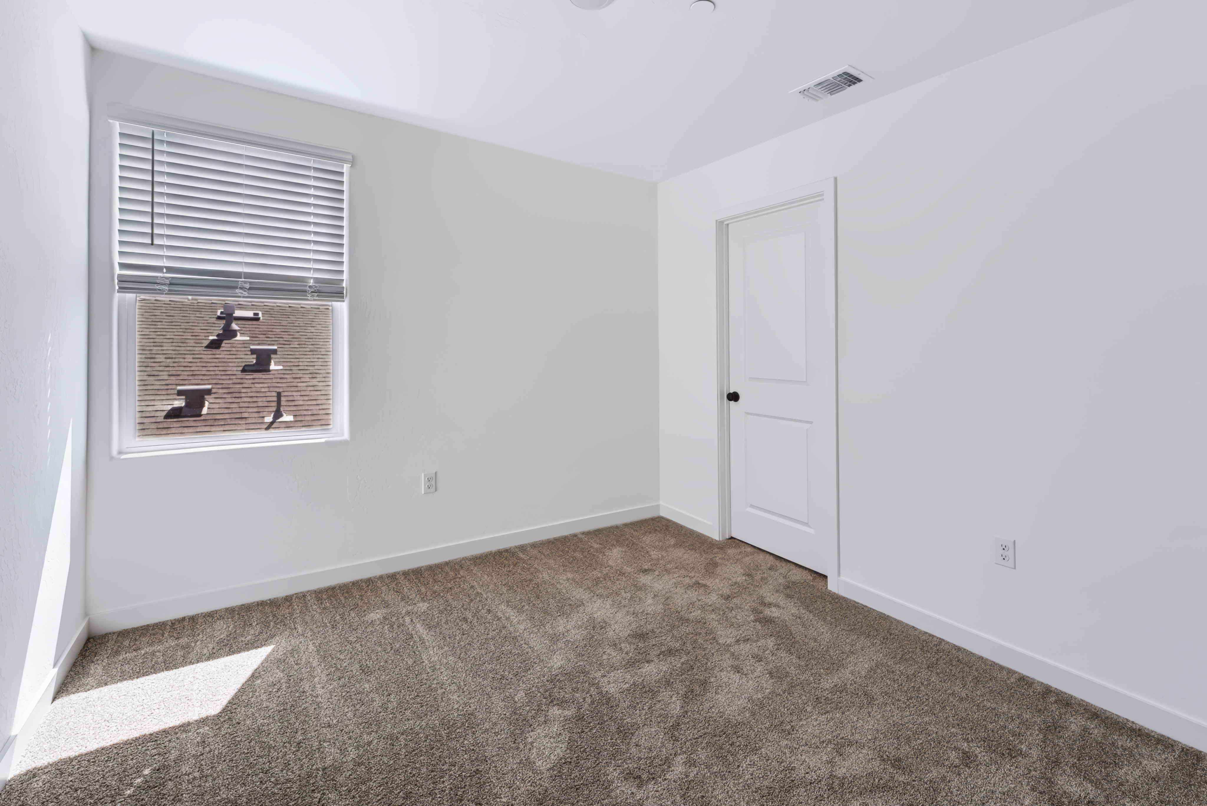 A room with a carpet and a door.