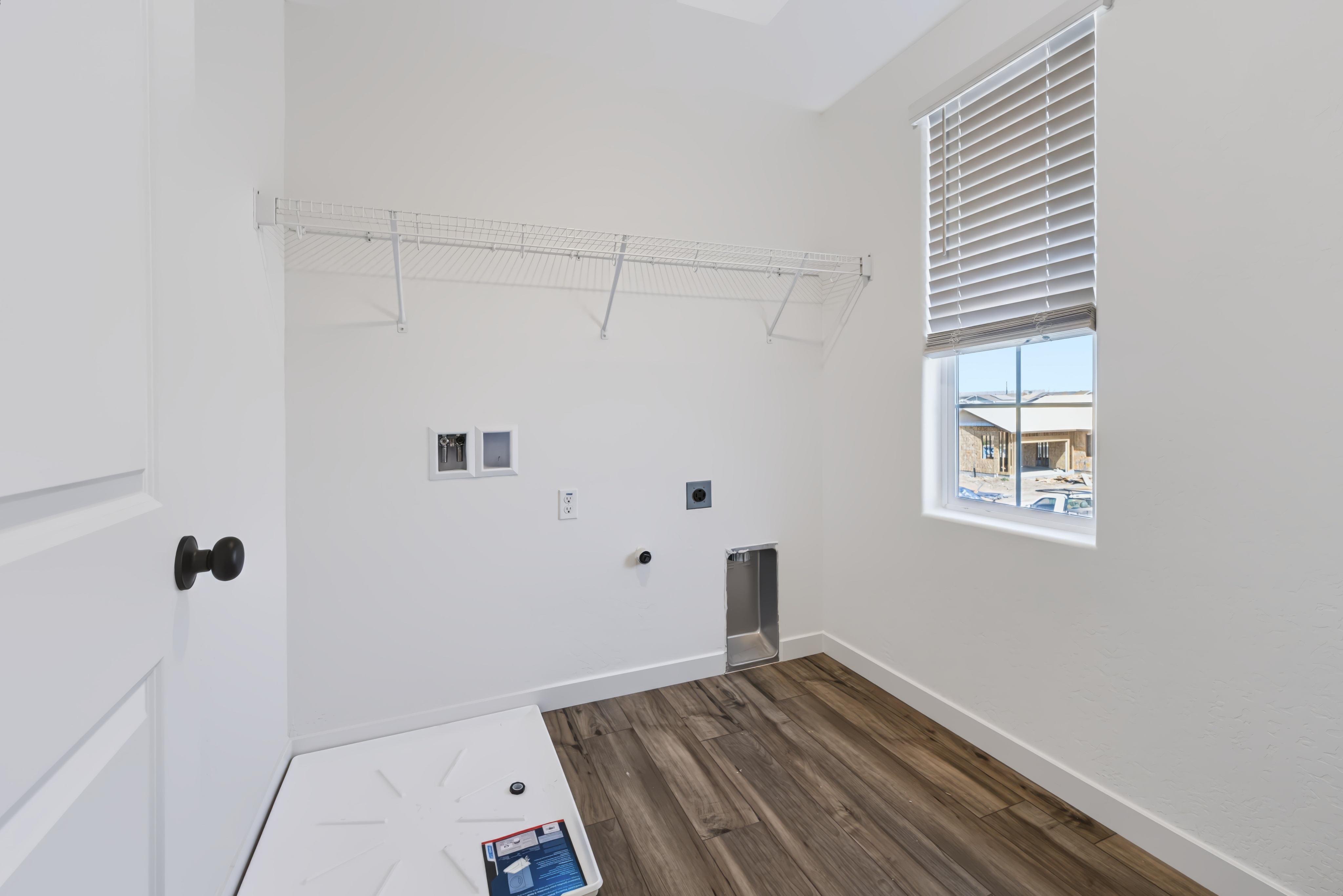A room with a wood floor and a window with blinds.