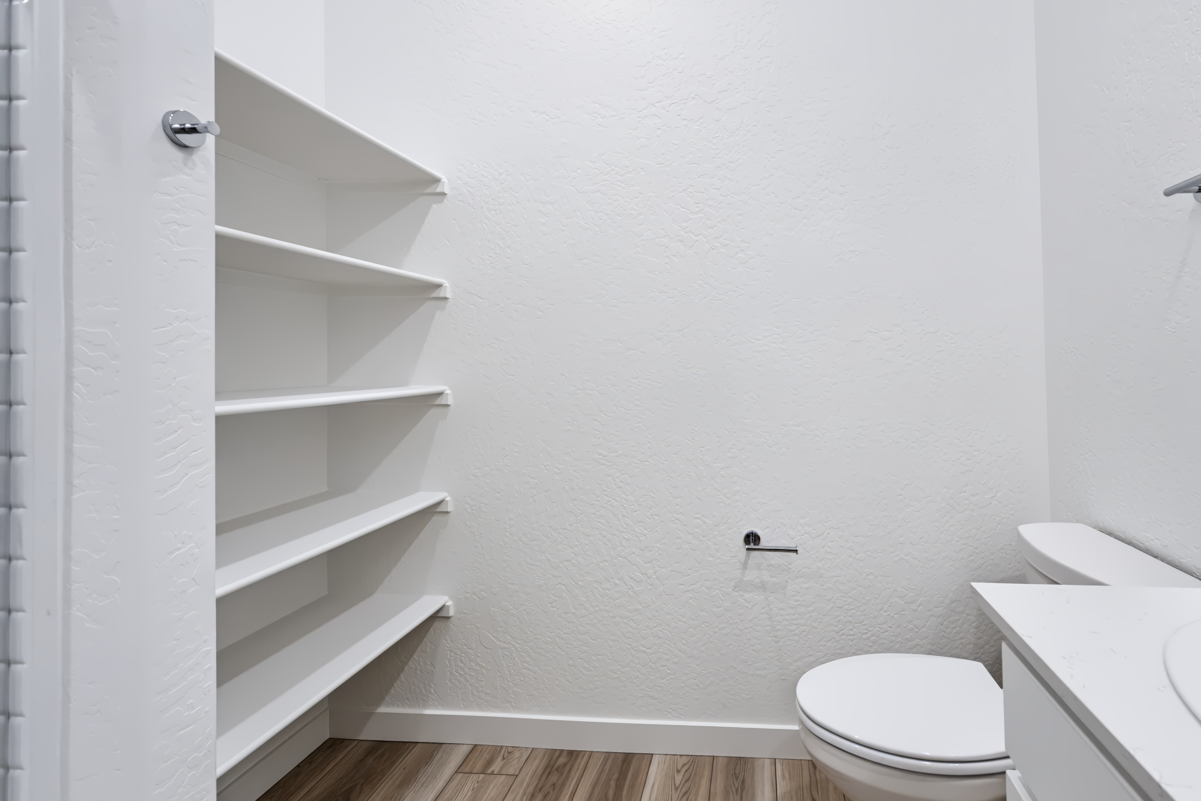 A white bathroom with a white shelf.
