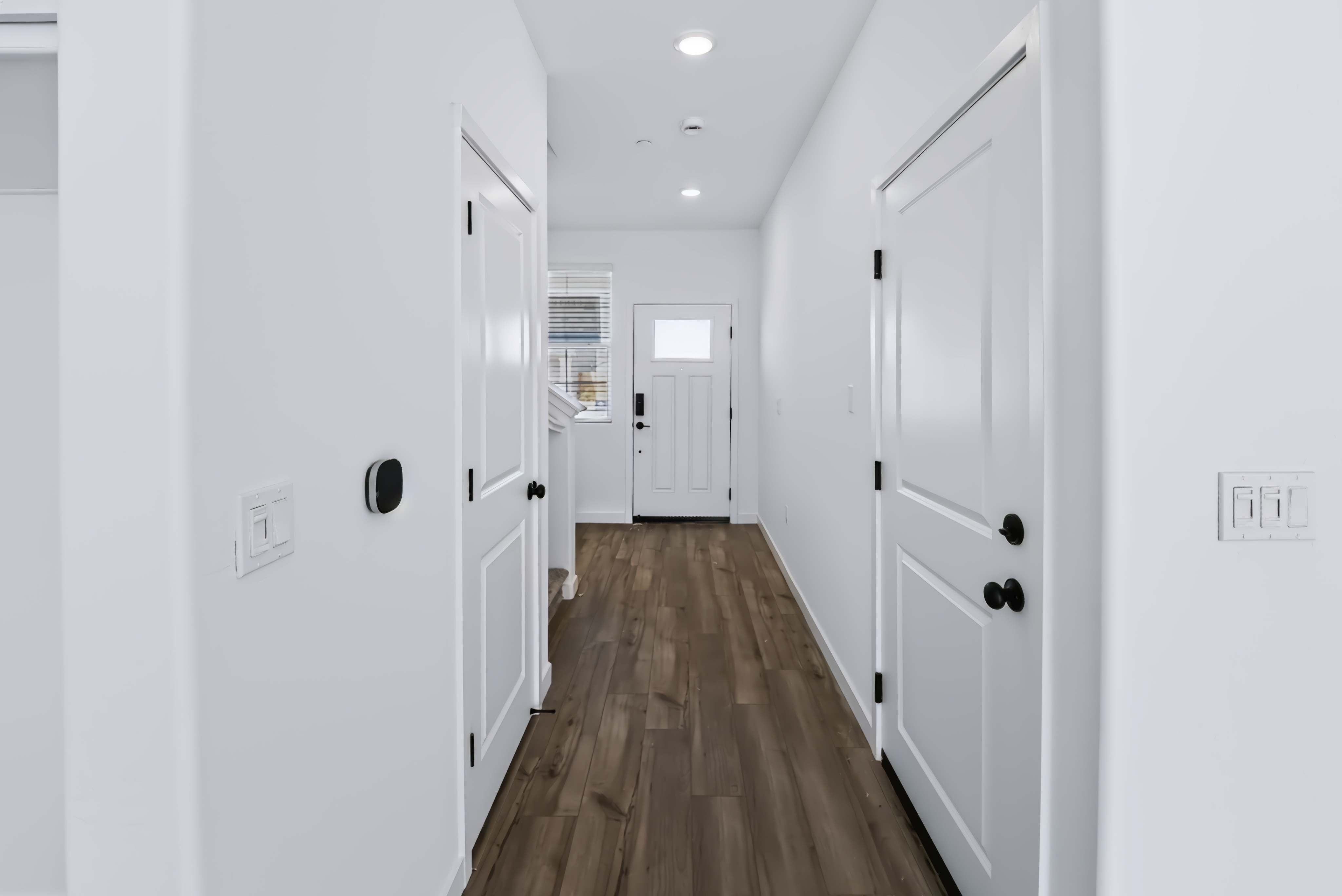A hallway with white cabinets.