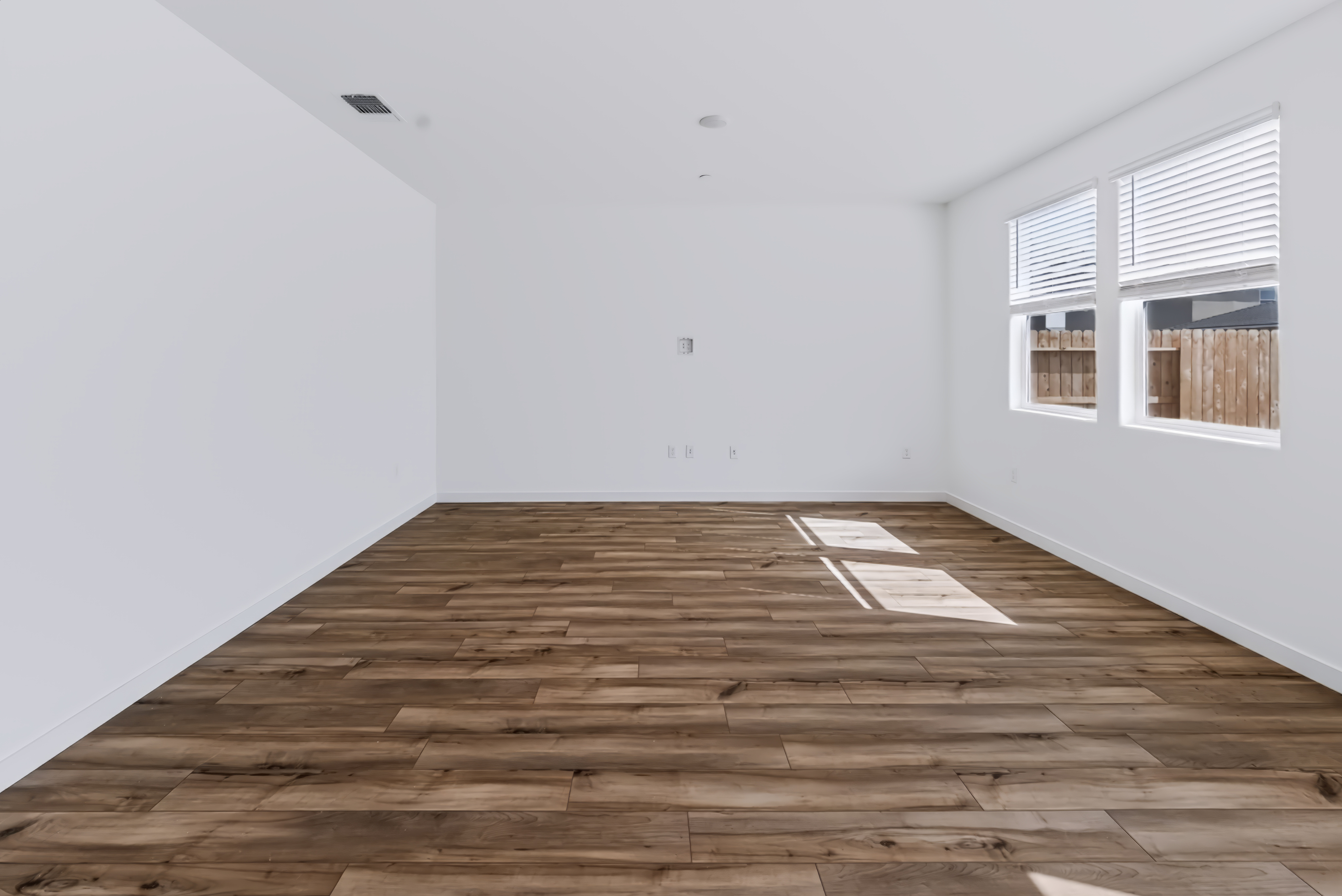 A room with a wood floor and windows.