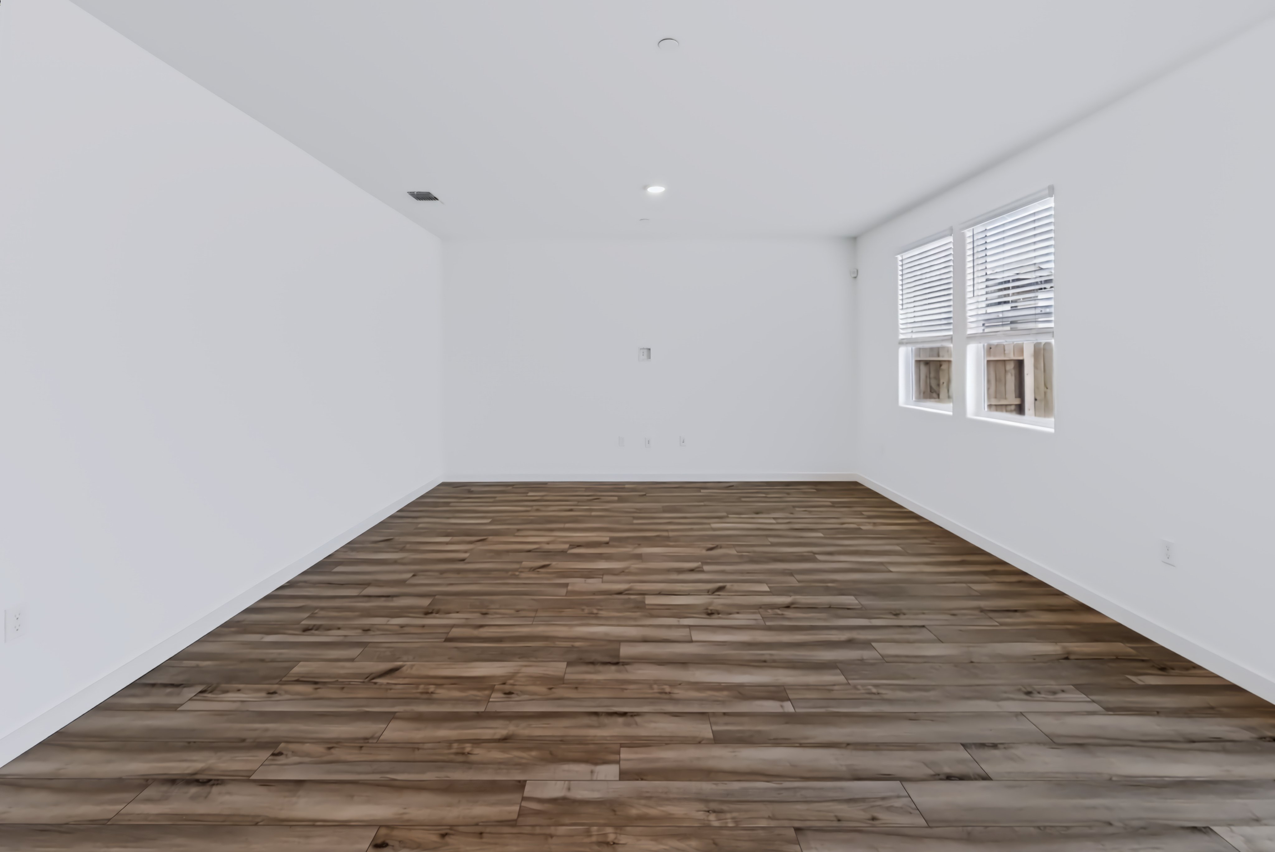 A room with a wood floor and windows.