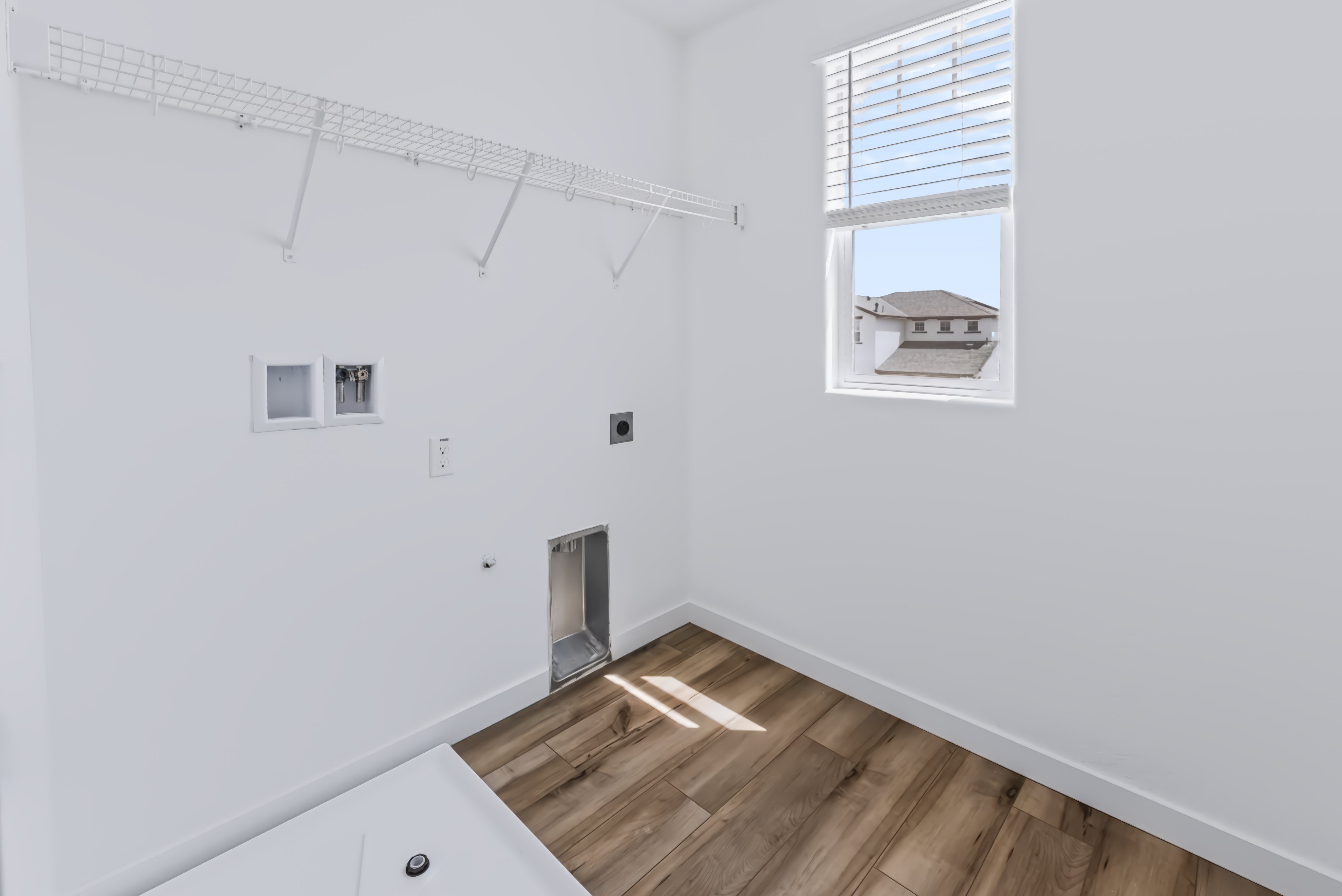 A room with a wood floor and a window with a vent.