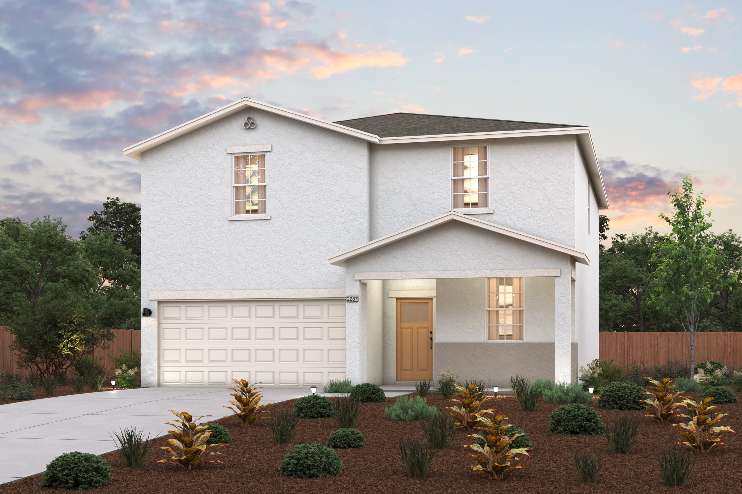 A house with a garage and bushes in front of it.