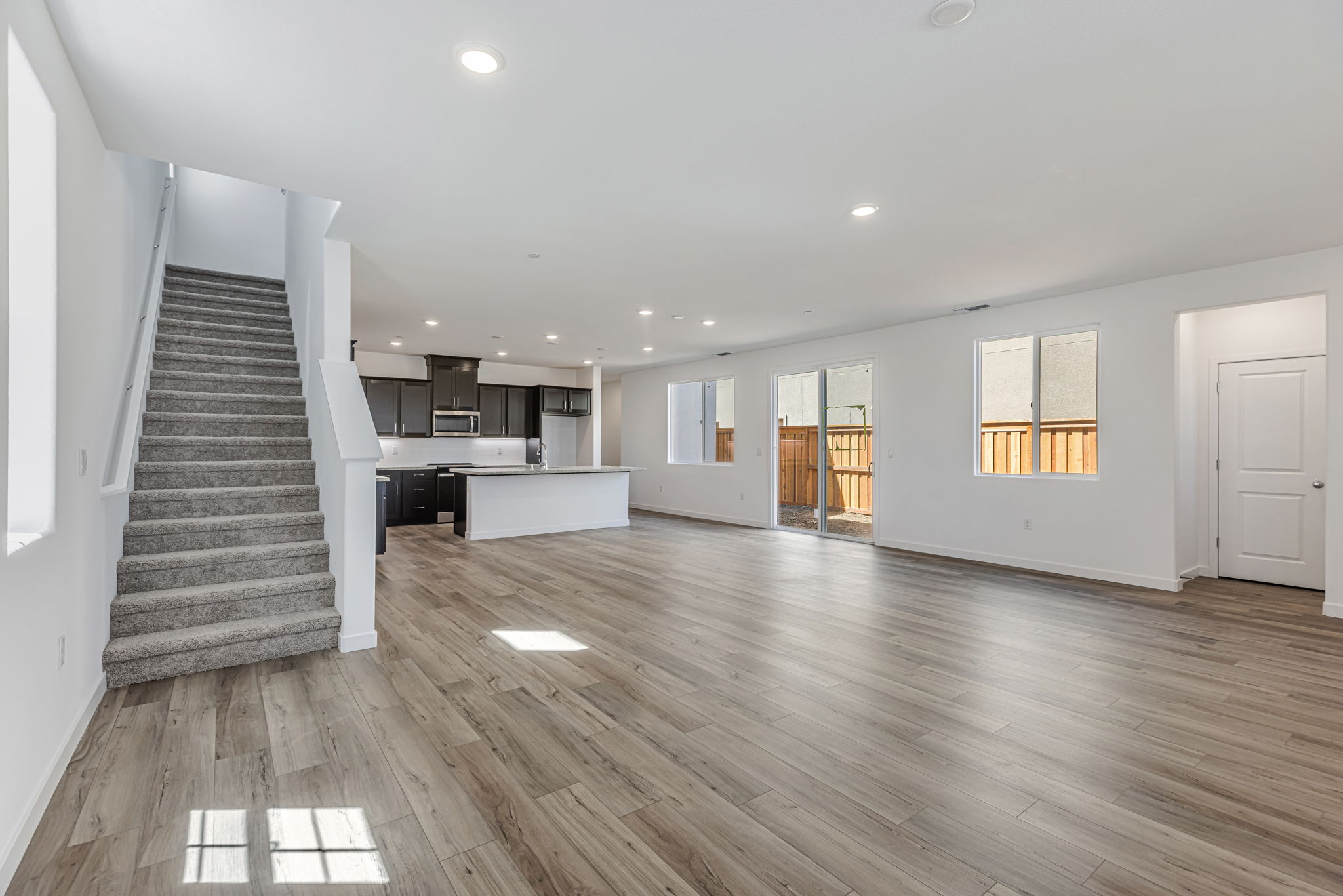 A large empty room with a wood floor and a staircase.
