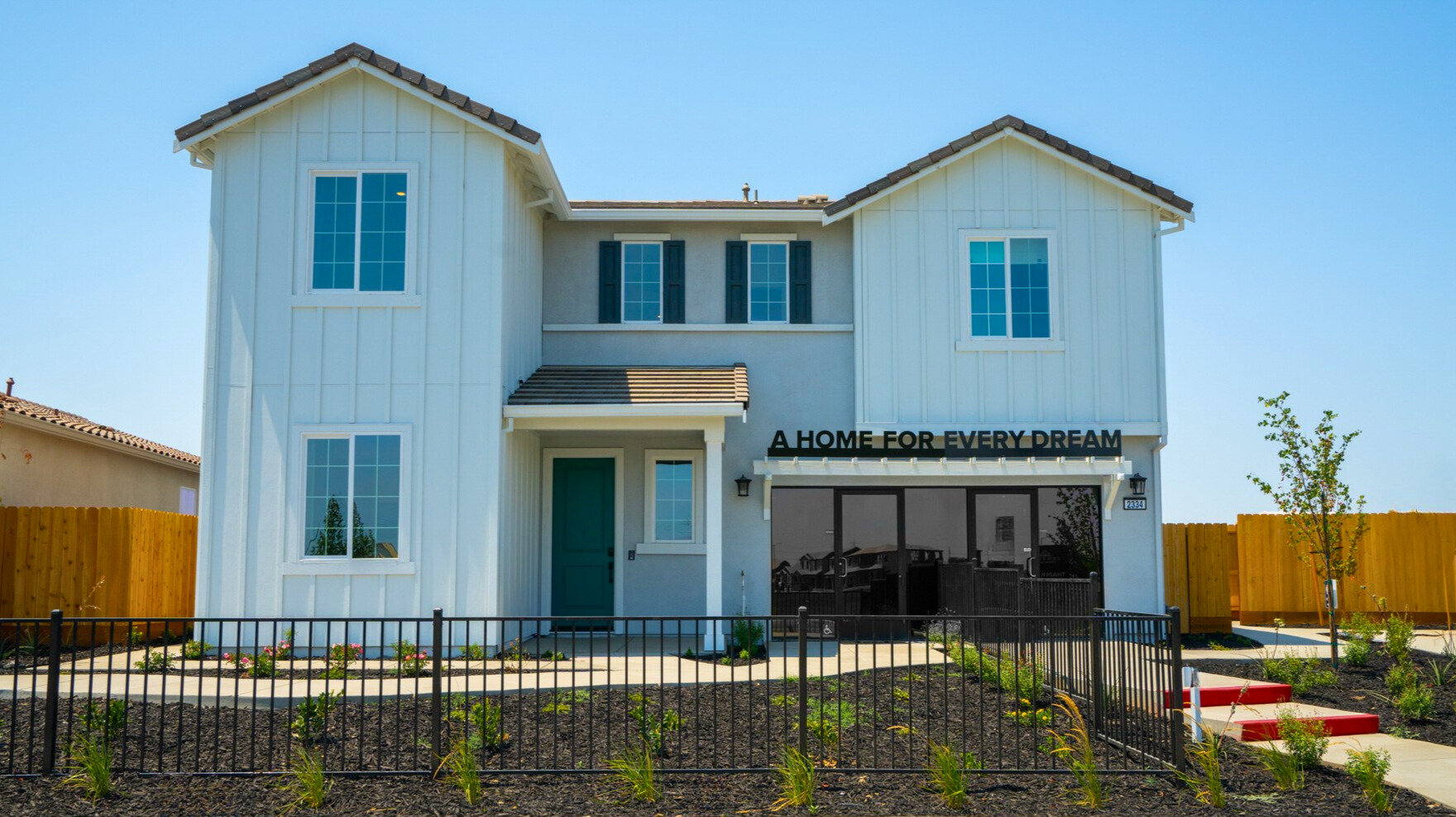 A white building with a black fence.