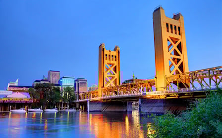A bridge over a river with buildings in the background.